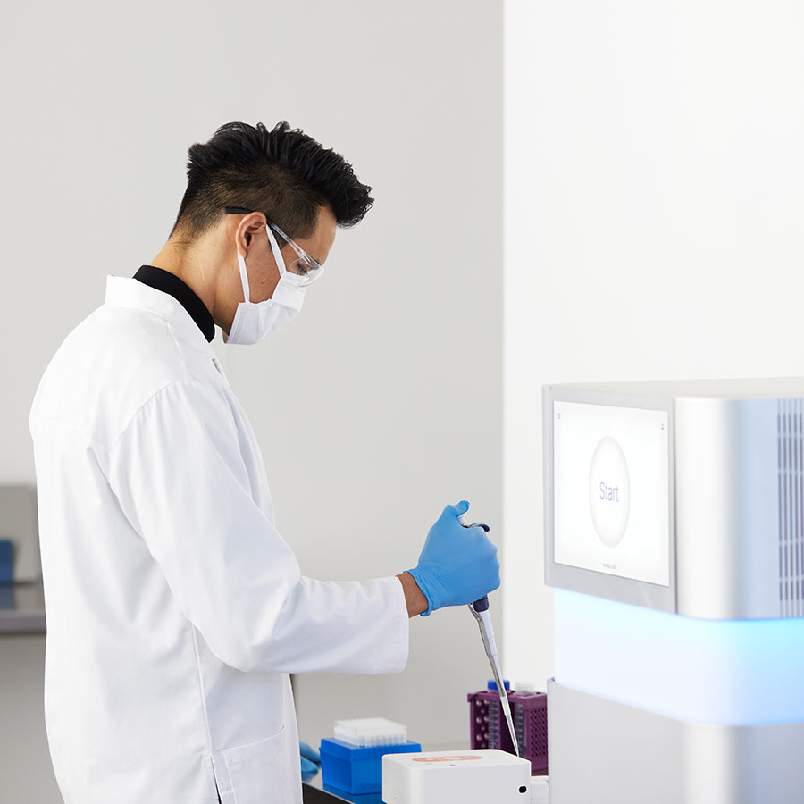 man in white lab coat wearing a white mask and blue gloves using a liquid dropper